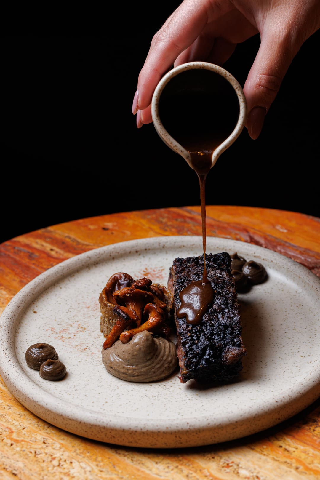 Jus poured over a short rib at the pass