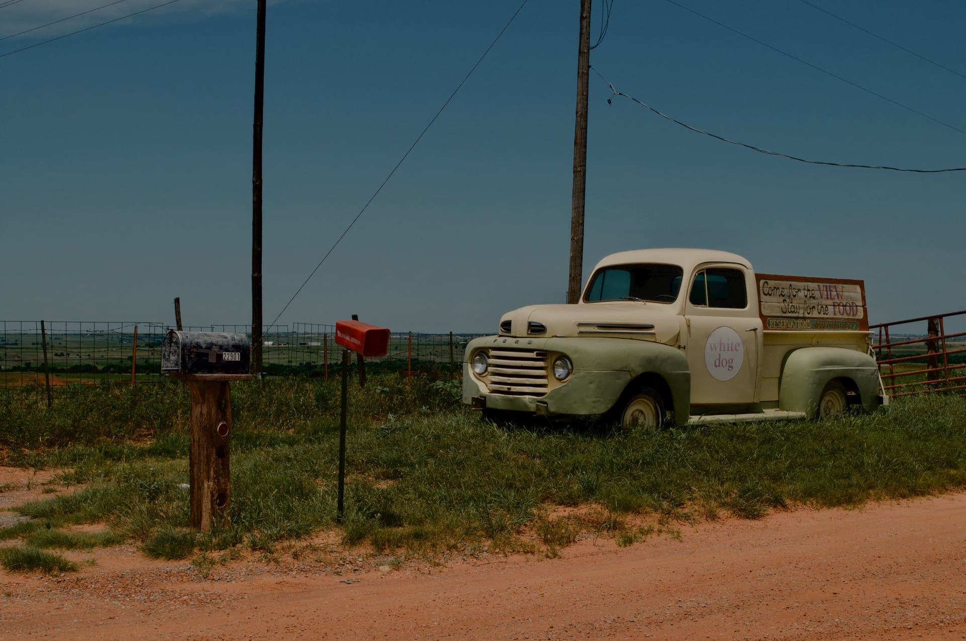 A vintage pickup truck parked by a roadside barbecue joint